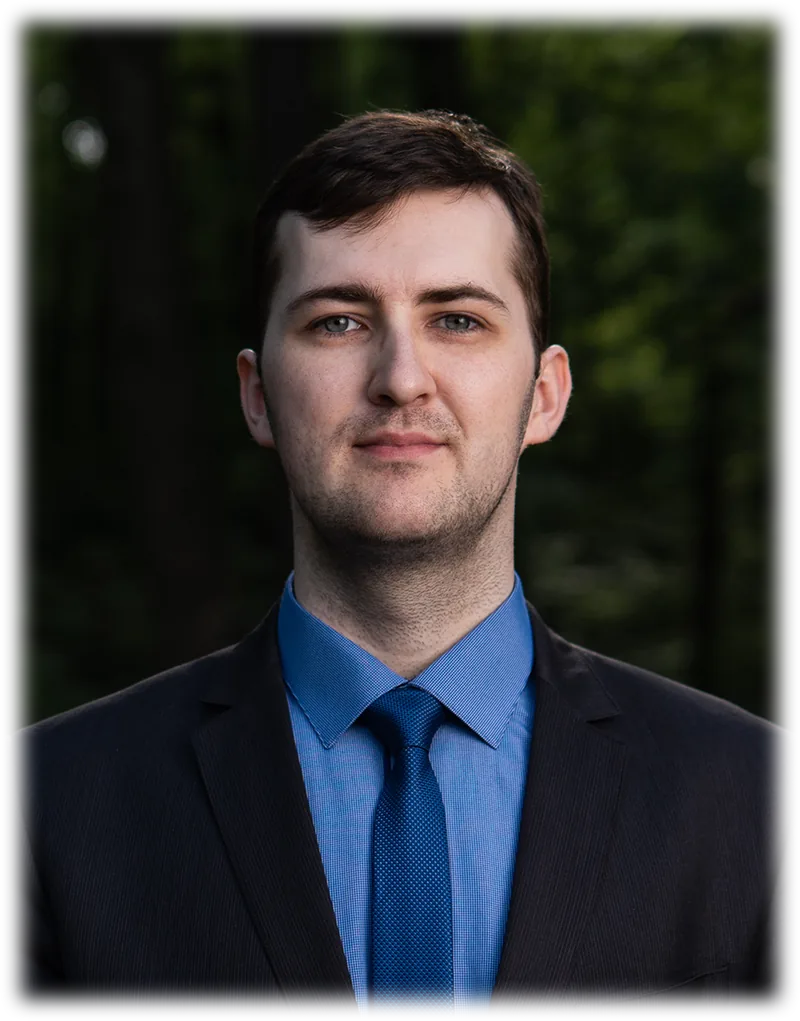 Yevhen Bataltsev, colour portrait in a dark suit and blue tie, photographed outdoors.